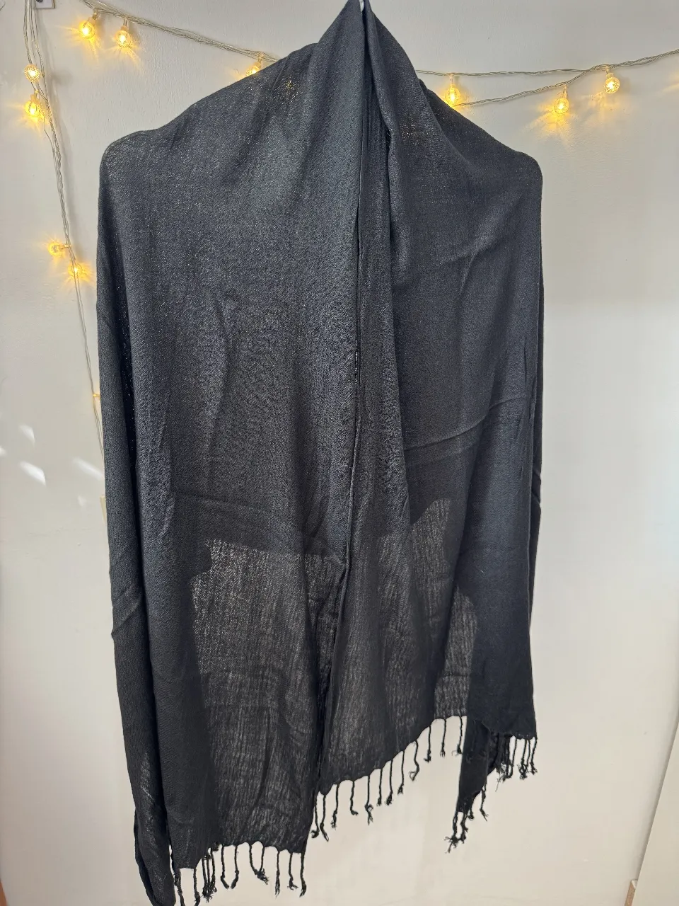 Bufanda negra de tela fina, ideal para complementar cualquier look. Perfecta para usar en diferentes ocasiones, desde salidas casuales hasta eventos más formales. Un accesorio versátil y elegante.