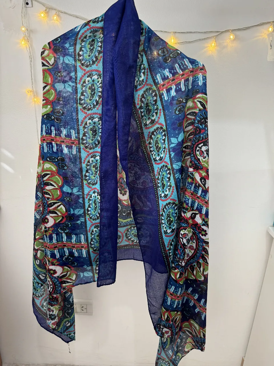 Pañuelo de seda con estampado floral en tonos azules y detalles en rojo y verde. Ideal para complementar cualquier look con un toque de color y estilo.