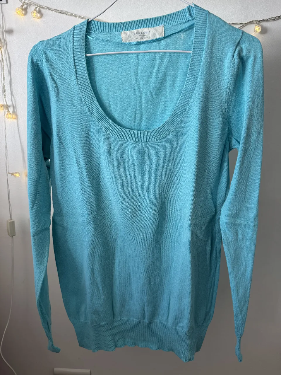 Sweater celeste de punto, con cuello en V y mangas largas. Ideal para un look casual y cómodo.