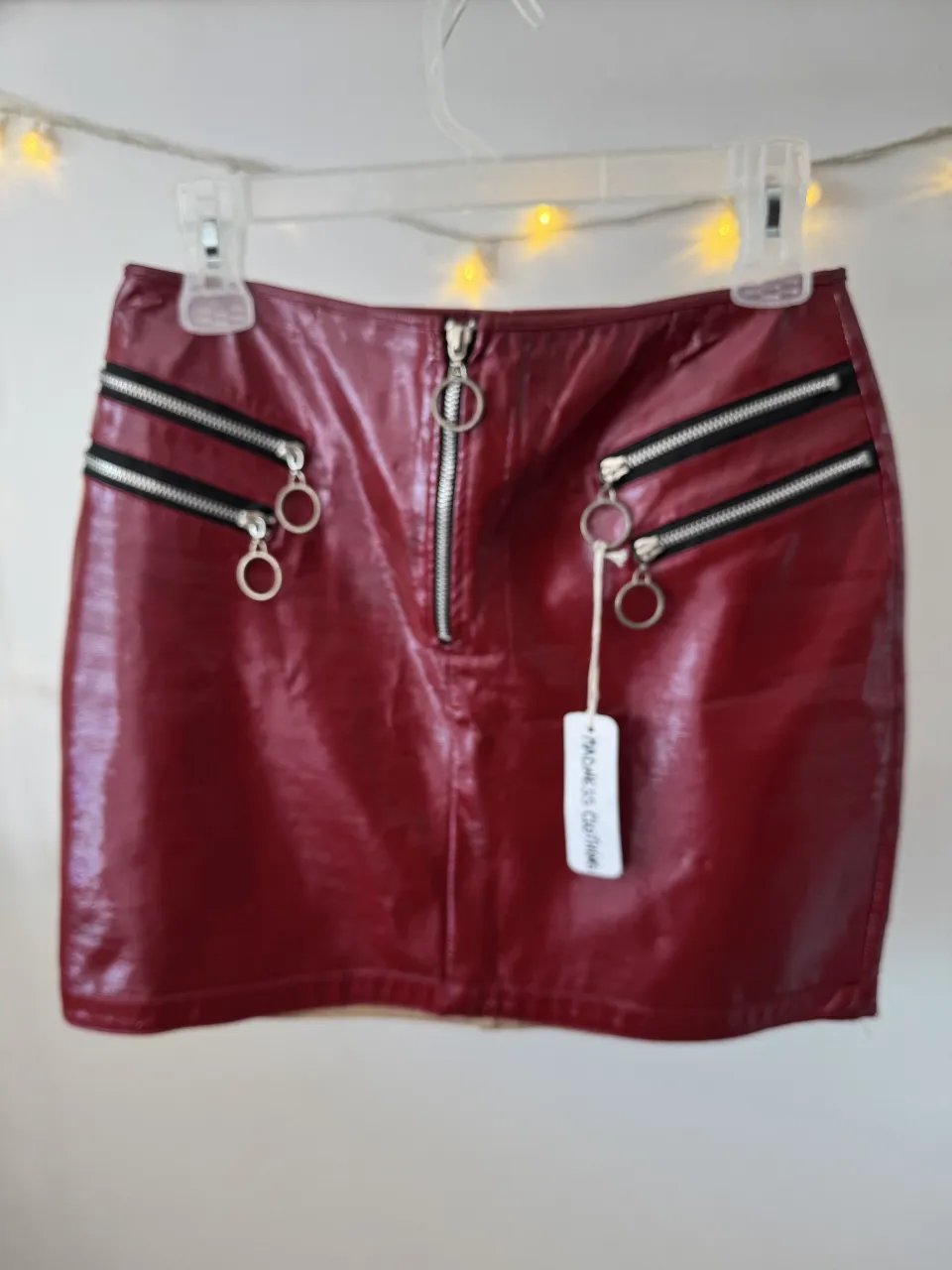 Minifalda de cuero sintético color borgoña con detalles de cierres y argollas. Ideal para un look rocker o de fiesta.