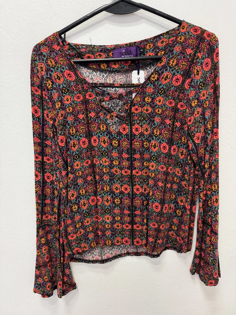 Blusa de manga larga con estampado floral en tonos vibrantes. Diseño con escote en V y detalle de cordones. Ideal para un look bohemio y con estilo.