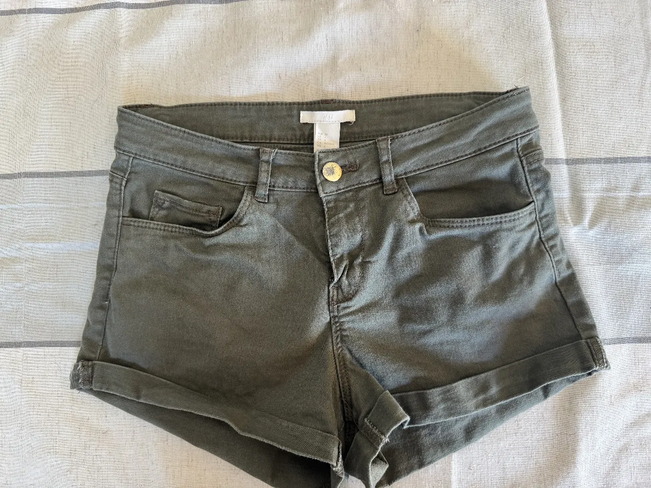 Short de jean verde militar de mujer, tiro medio, con bolsillos delanteros y traseros. Ideal para un look casual y cómodo.