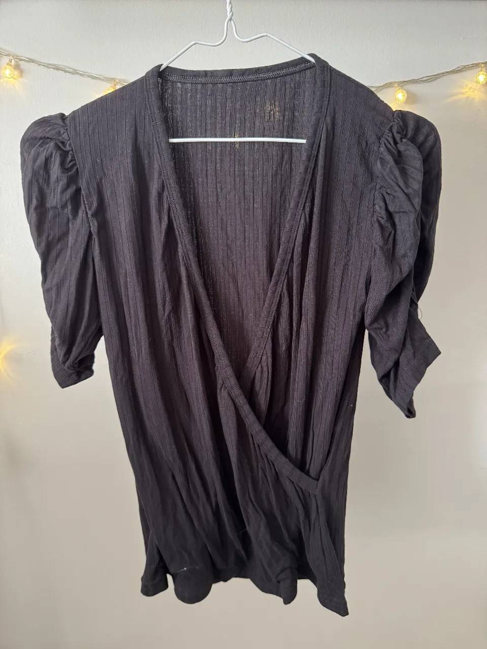Blusa negra con mangas abullonadas y escote en V. Ideal para un look elegante y sofisticado.