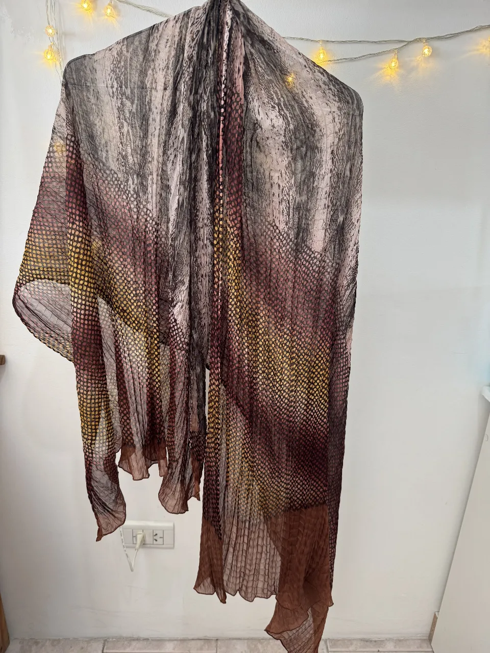 Pañuelo de seda con estampado abstracto en tonos marrones, amarillos y grises. Ideal para complementar cualquier look con un toque de elegancia y sofisticación.