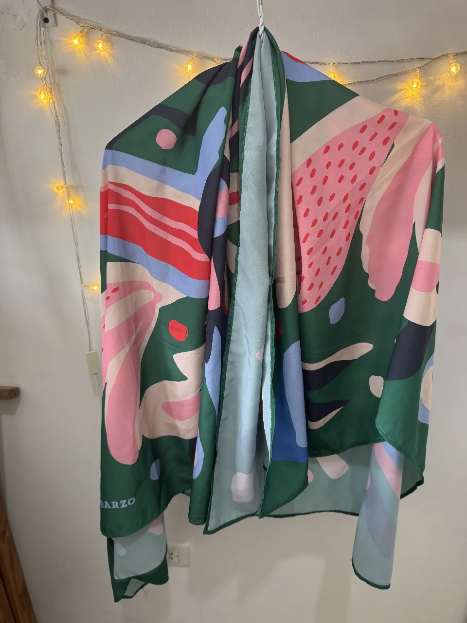 Pañuelo de seda con estampado abstracto en tonos verdes, rosas, azules y rojos. Ideal para darle un toque de color y estilo a cualquier look.