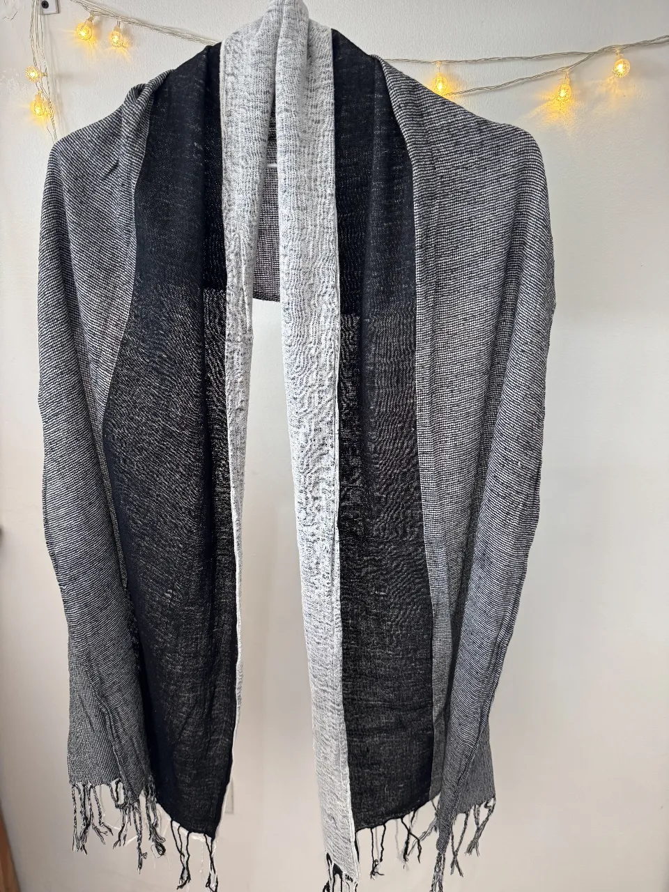 Bufanda de diseño bicolor en tonos grises y negro, con flecos en los extremos. Ideal para complementar cualquier look de invierno.