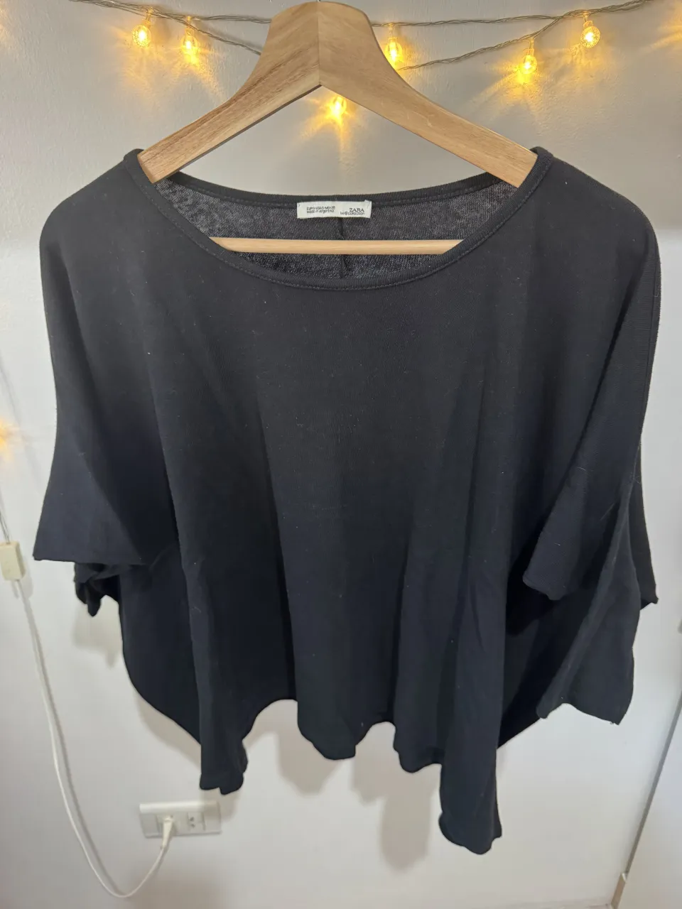 Remera negra de manga corta y escote redondo. Diseño amplio con terminación irregular en la parte inferior.