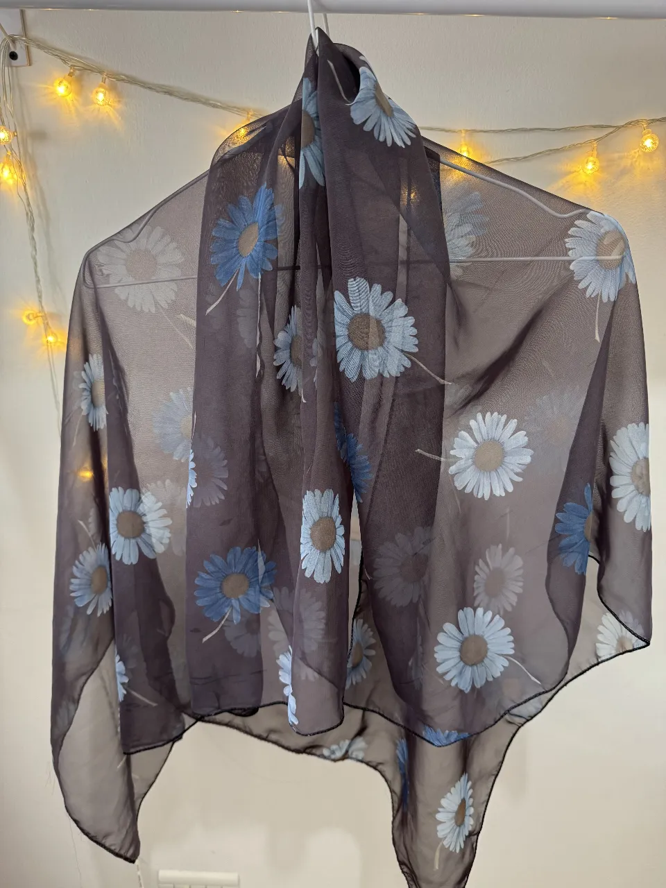 Pañuelo de seda marrón con estampado floral en tonos azules y blancos. Ideal para complementar cualquier look femenino con un toque de elegancia y estilo.