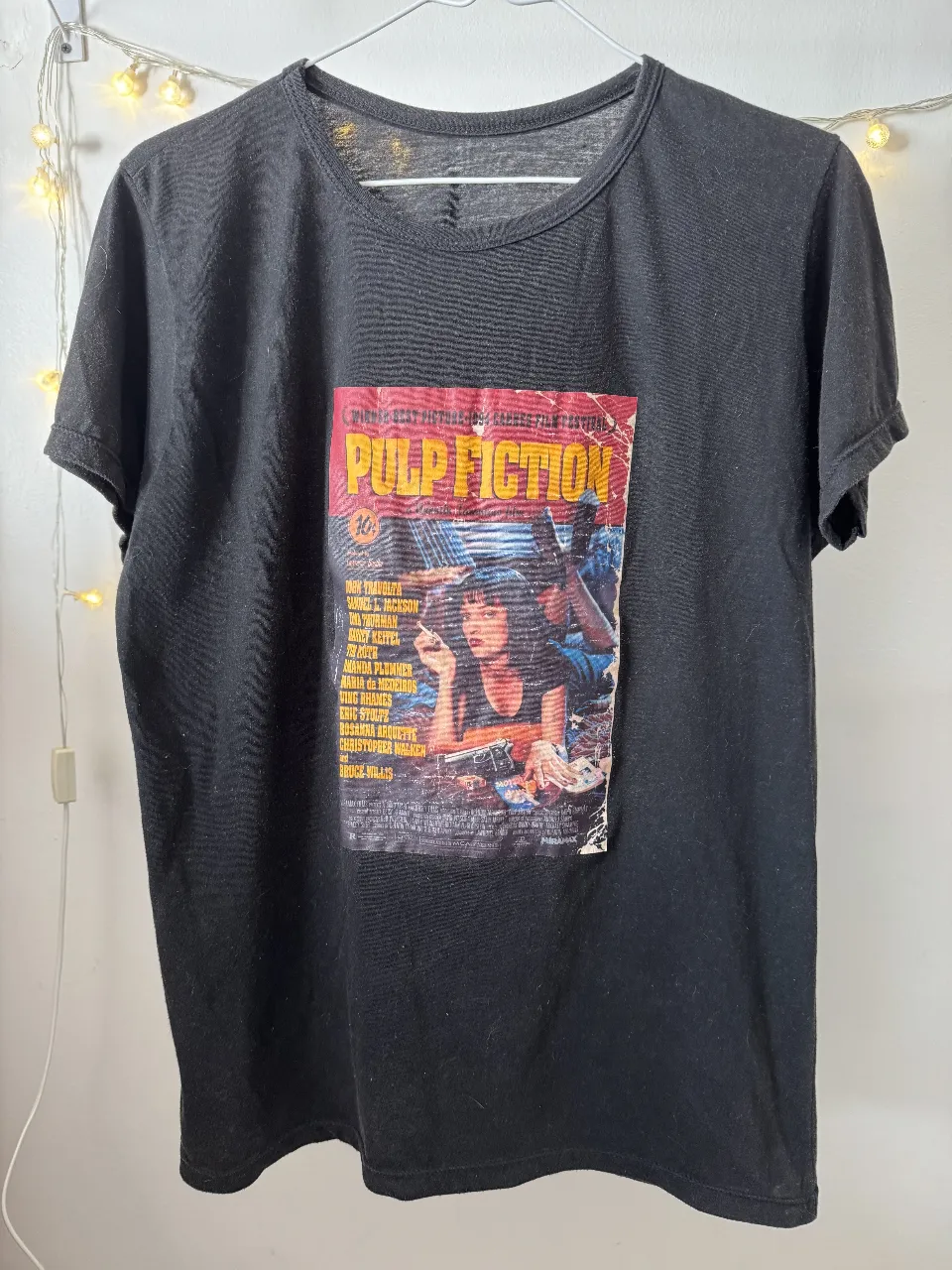 Remera negra de algodón con estampado frontal del icónico afiche de la película Pulp Fiction. Ideal para un look casual y con onda.