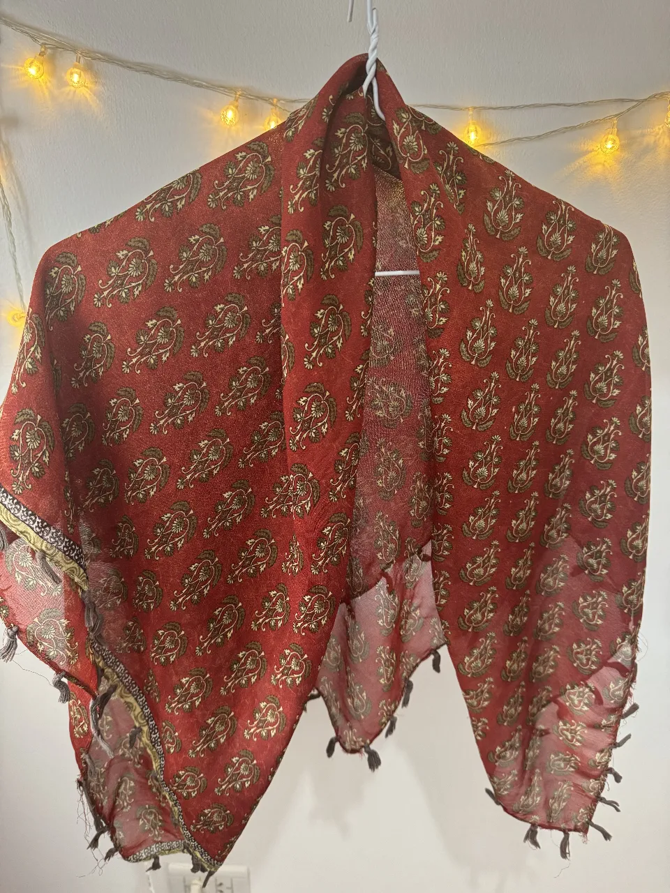 Pañuelo de seda rojo con estampado floral en tonos dorados y detalles en negro. Ideal para complementar cualquier look con un toque bohemio y elegante.