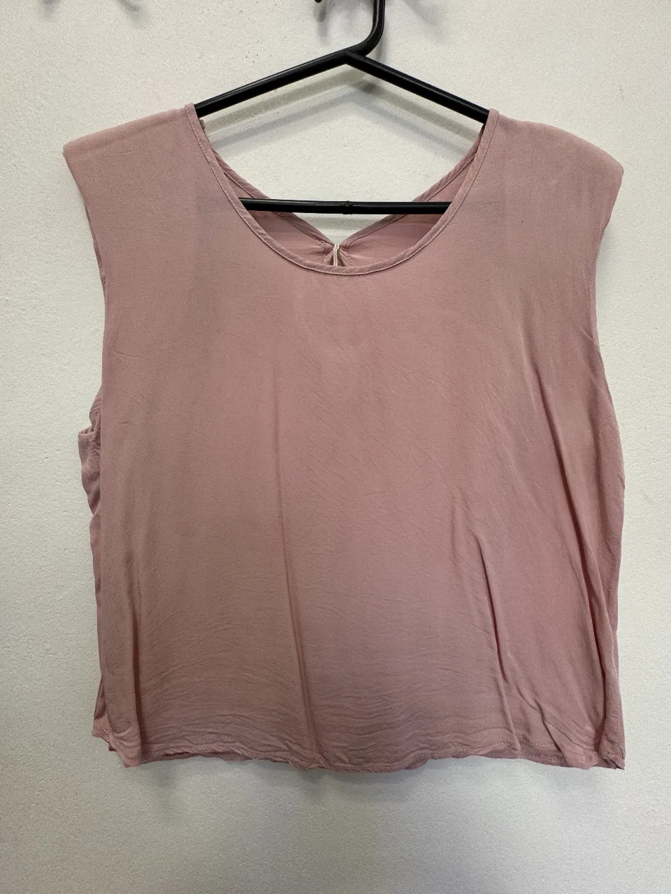 Top sin mangas de color rosa, con hombreras y diseño de espalda descubierta y detalle de abertura. Ideal para un look casual y fresco.