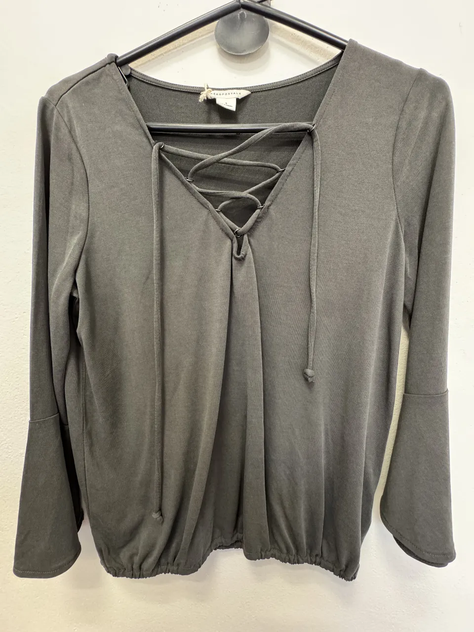 Blusa gris con detalle de lazada en el escote y mangas acampanadas. Ideal para un look casual y moderno.