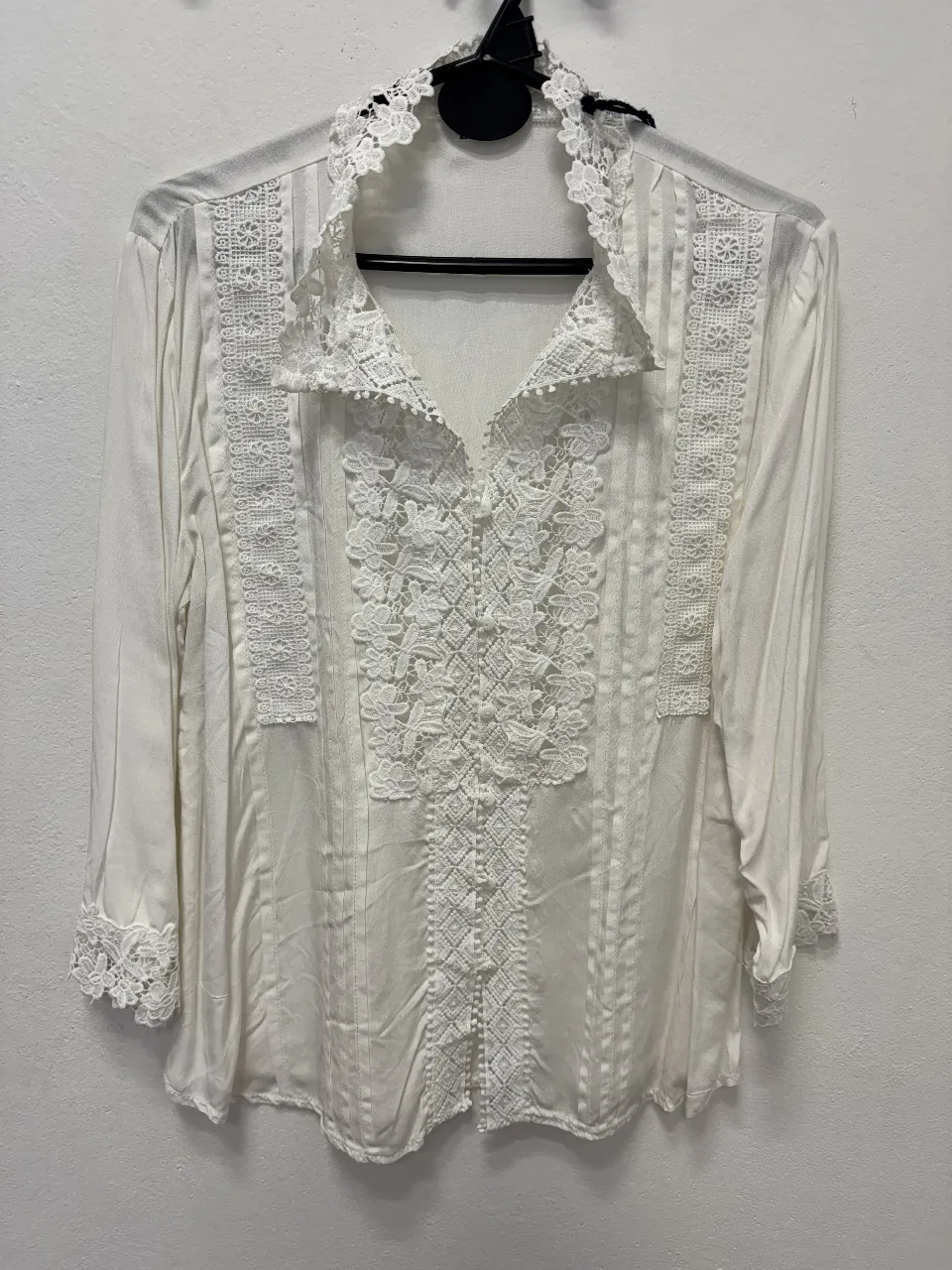 Blusa blanca con detalles de encaje, ideal para un look romántico y elegante. Perfecta para combinar con pantalones de vestir o faldas.