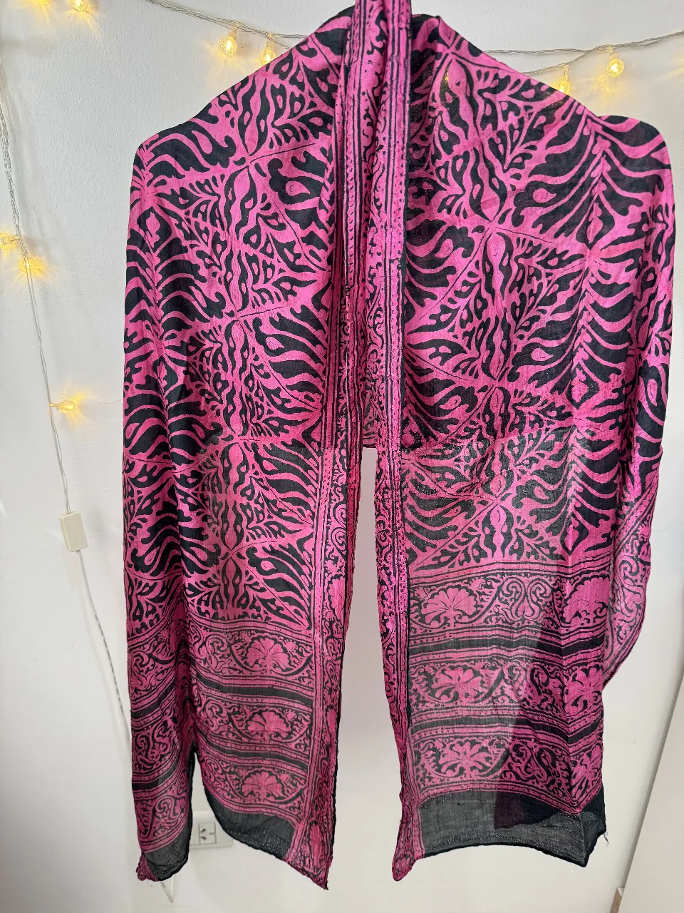 Pañuelo de seda con estampado floral en tonos rosa y negro. Ideal para complementar cualquier look con un toque de elegancia y estilo.