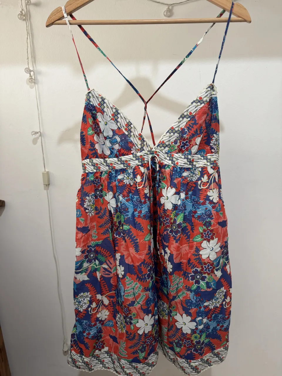 Vestido corto estampado floral con tiras finas cruzadas en la espalda. Posee elástico en la cintura y detalle de lazo.