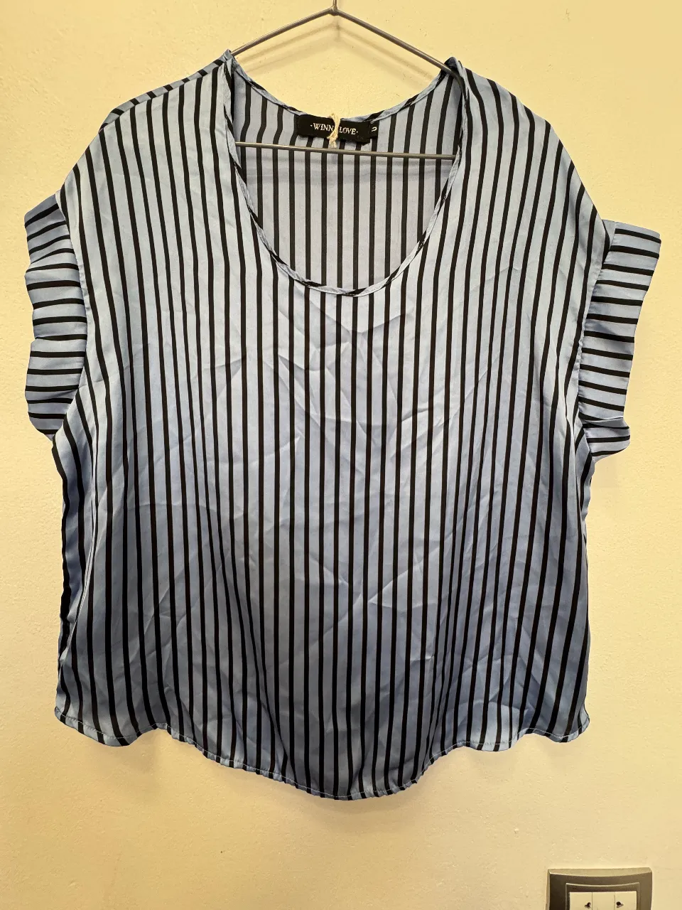 Blusa de mujer con estampado de rayas verticales en tonos celeste y negro. Diseño con mangas cortas con volados y cuello redondo. Ideal para un look fresco y moderno.