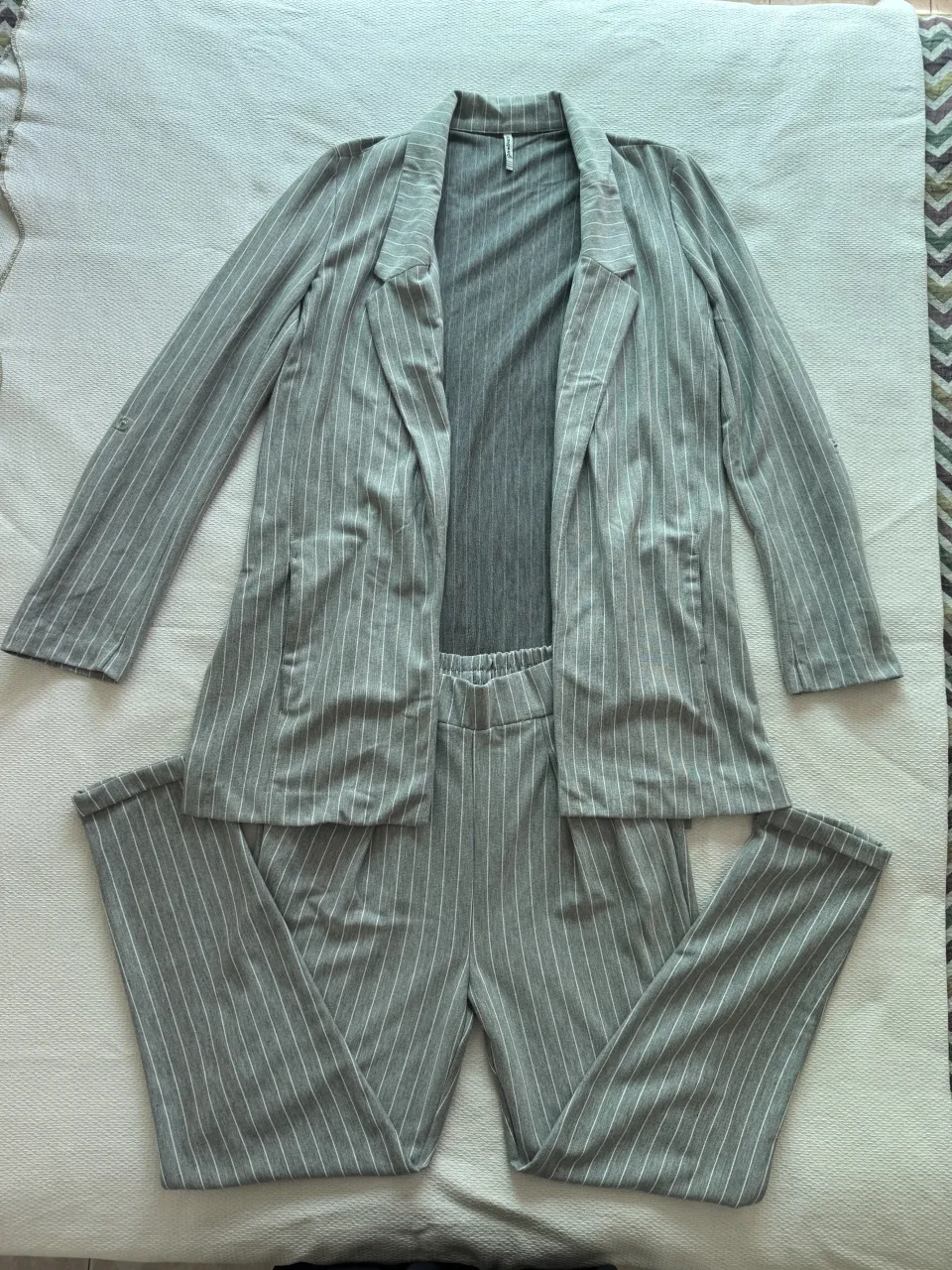 Conjunto de blazer y pantalón a rayas grises con detalles blancos.