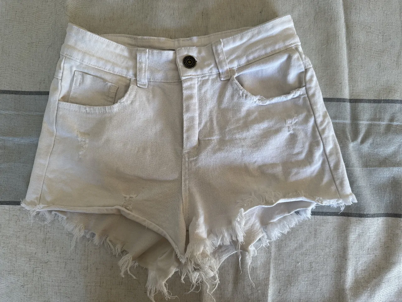 Short de jean blanco con detalles rotos y flecos en el borde. Talle 36 de la marca Bora. Ideal para un look casual y fresco.