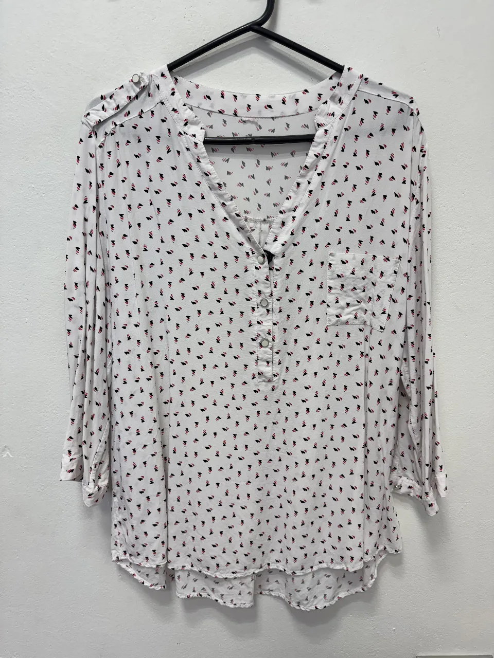 Blusa de mujer con estampado de figuras geométricas en blanco y negro. Cuello en V, manga 3/4 y botones. Ideal para un look casual y elegante.