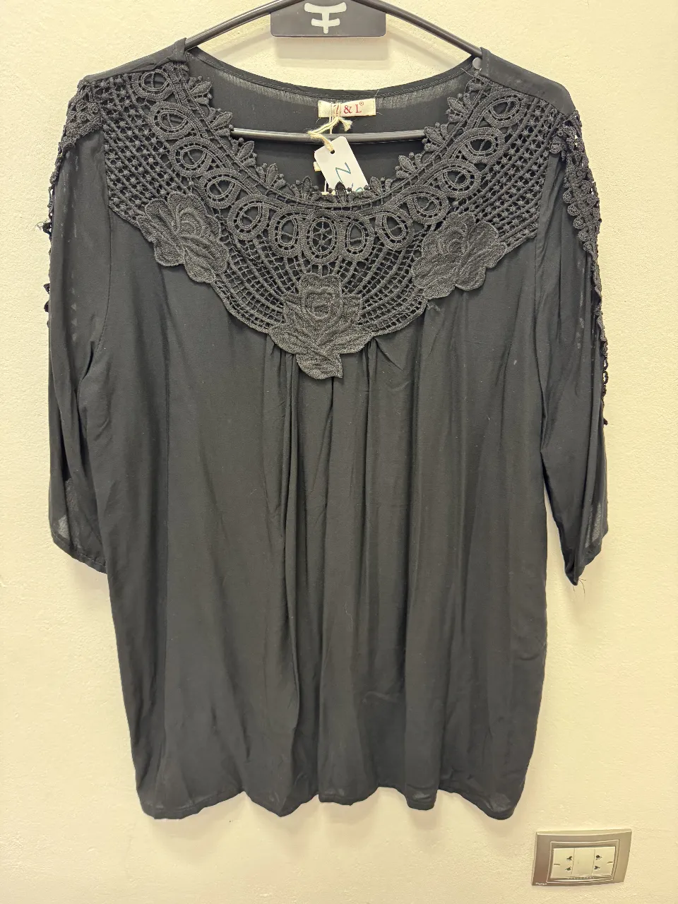 Blusa negra con detalle de encaje en el cuello y mangas 3/4. Ideal para un look elegante y sofisticado.