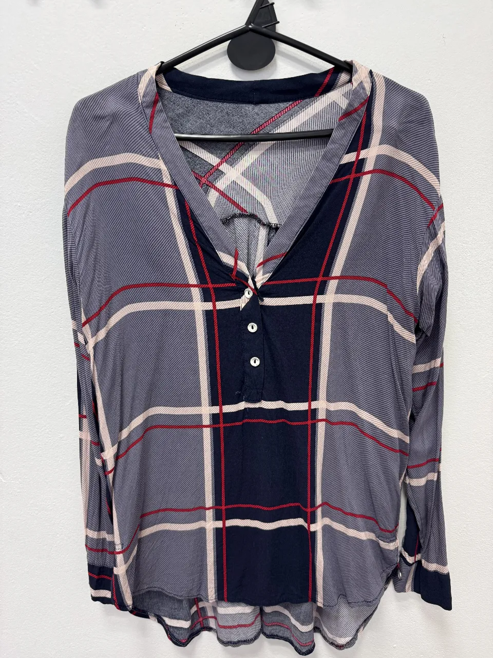 Blusa de mujer con estampado a cuadros en tonos grises, rojos y blancos. Manga larga con botones y cuello en V. Ideal para un look casual y moderno.