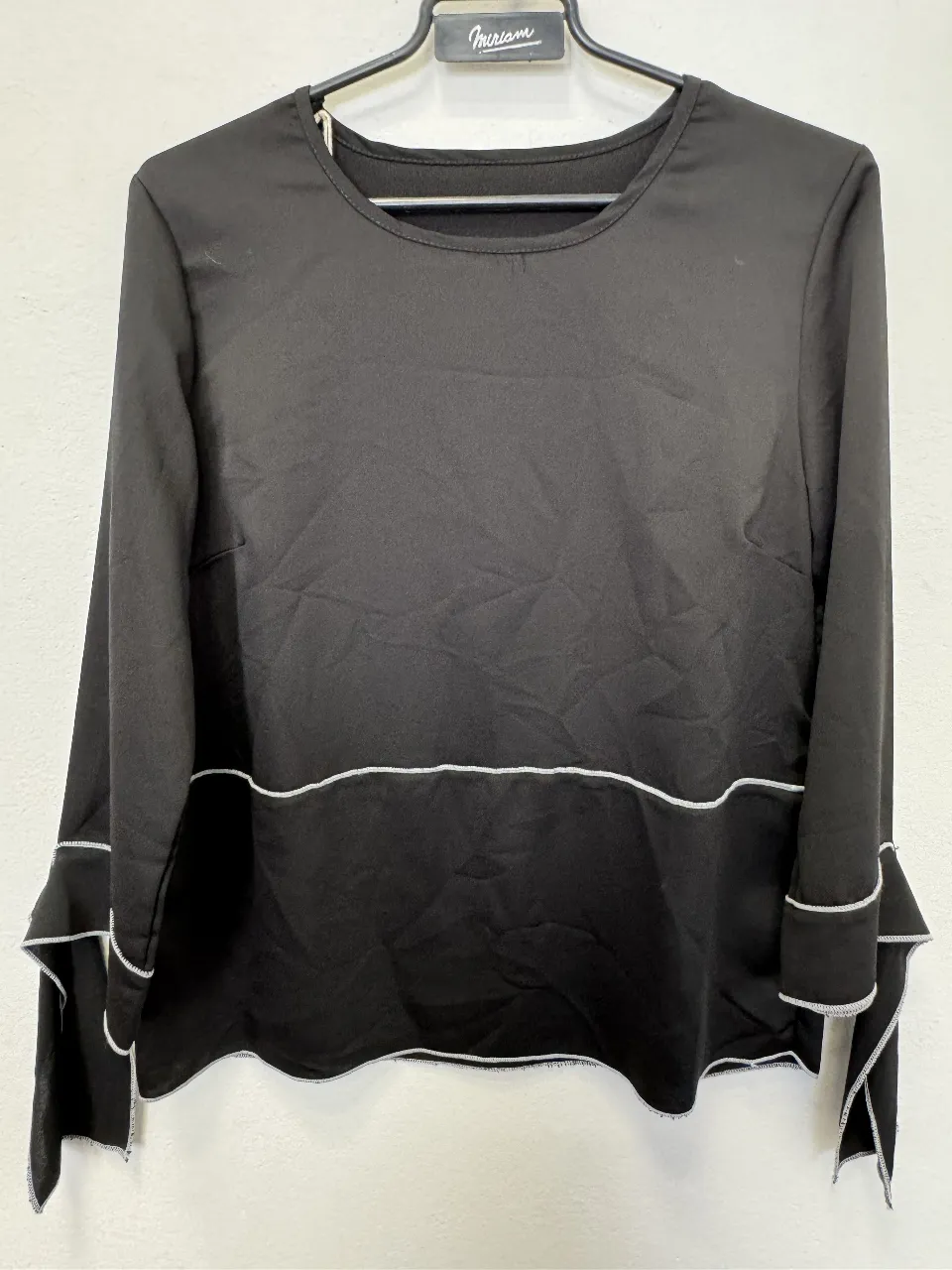 Blusa negra de manga larga con detalles en blanco. Diseño elegante con terminaciones en blanco en mangas y borde inferior. Ideal para un look sofisticado.