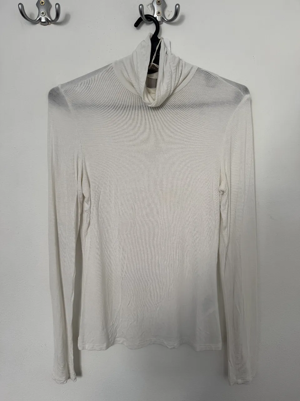 Remera de manga larga con cuello alto, de color blanco. Ideal para usar en capas o como prenda principal. Talle XS.