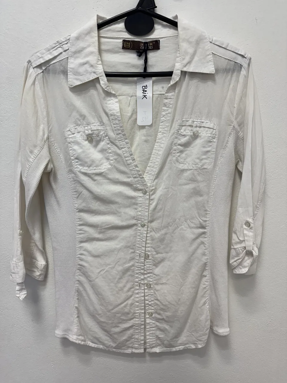 Camisa blanca de mujer, con mangas 3/4 y botones. Ideal para un look casual y versátil.