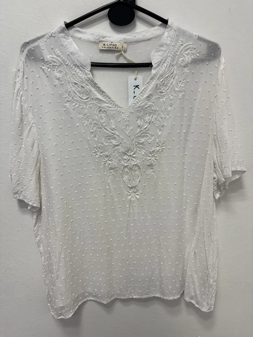 Blusa blanca con bordado en el frente y detalles de puntos. Ideal para un look fresco y casual.