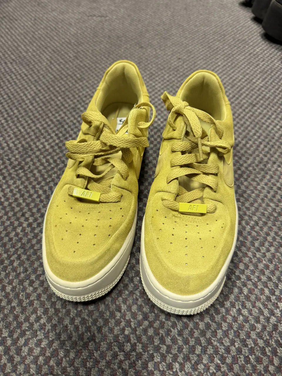 Zapatillas Nike Air Force 1 amarillas de gamuza, con detalles en blanco y etiqueta "AFT". Ideales para un look casual y moderno.