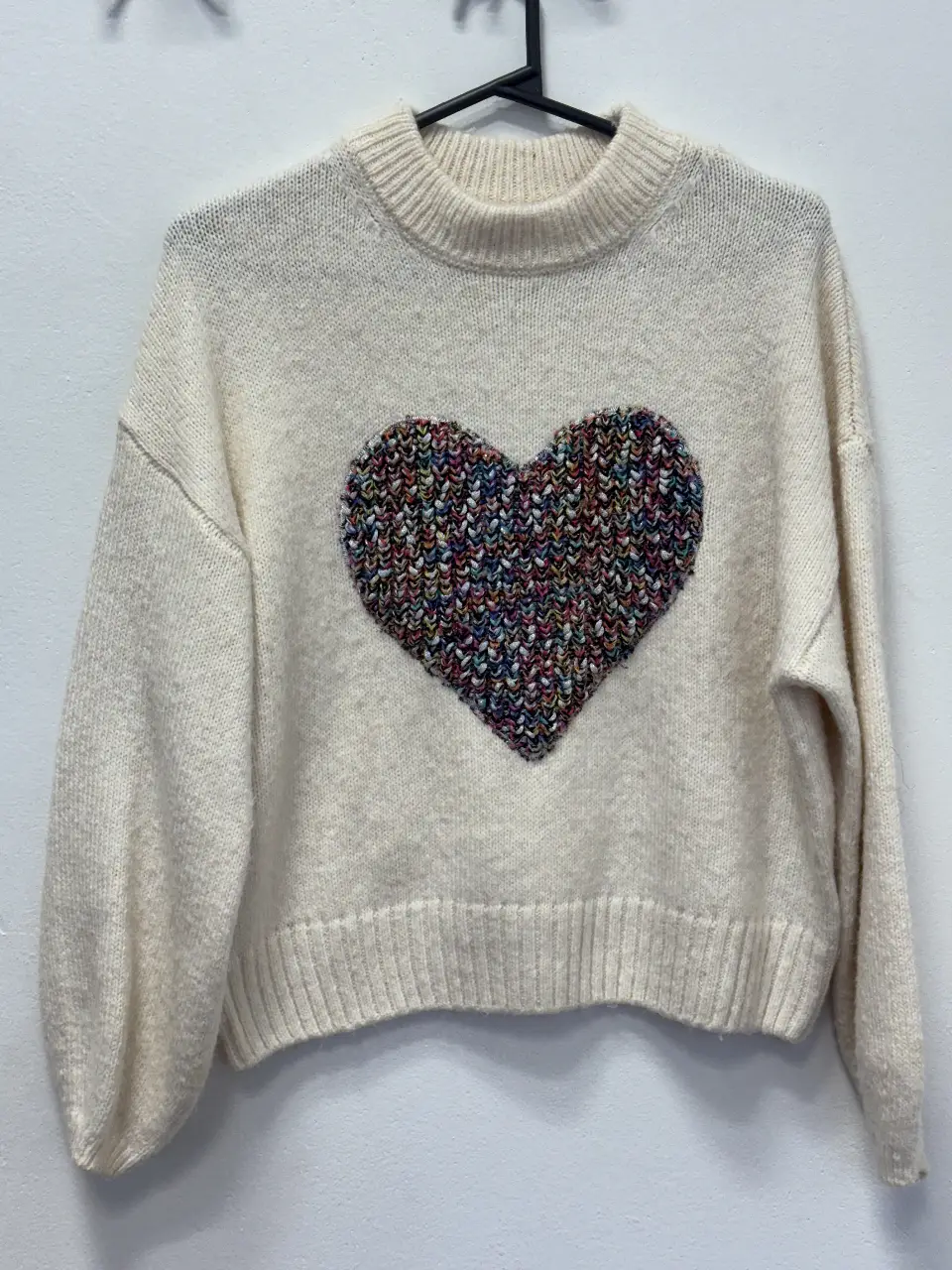 Sweater de lana color crema con un corazón multicolor en el frente. Ideal para un look casual y abrigado.