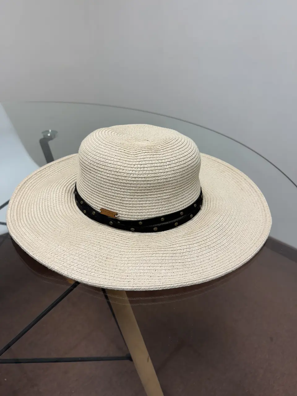 Sombrero de playa de color crudo con cinta negra y detalles metálicos. Ideal para protegerte del sol con estilo.