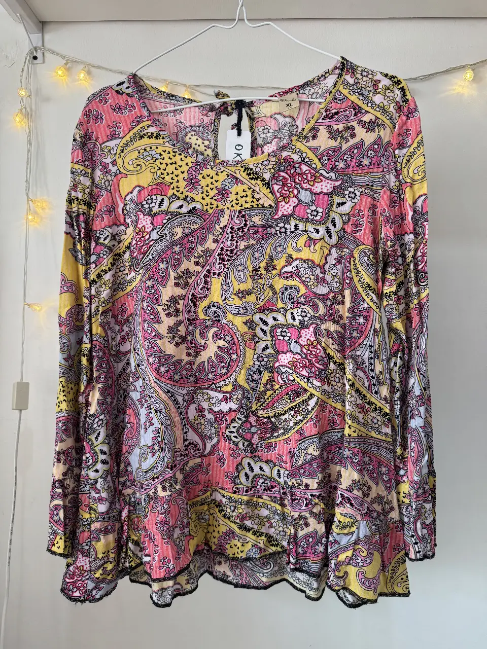 Blusa estampada con diseño paisley en tonos rosa y amarillo. Manga larga con detalle de volados en los puños y en el ruedo. Cuello en V. Ideal para un look bohemio y femenino.