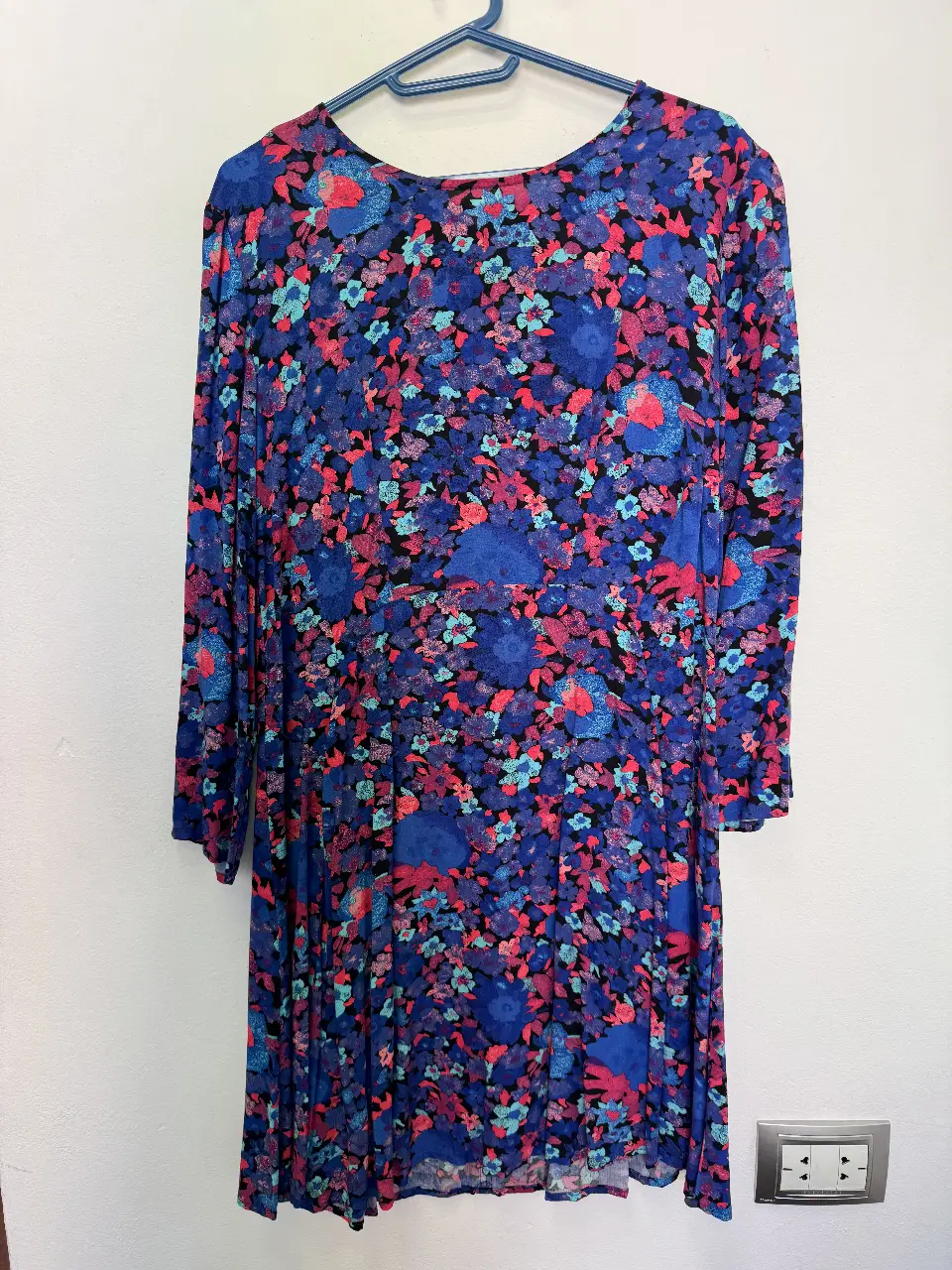 Vestido midi con estampado floral en tonos azules y rojos. Tiene mangas largas y cierre en la espalda. Ideal para un look casual y femenino.