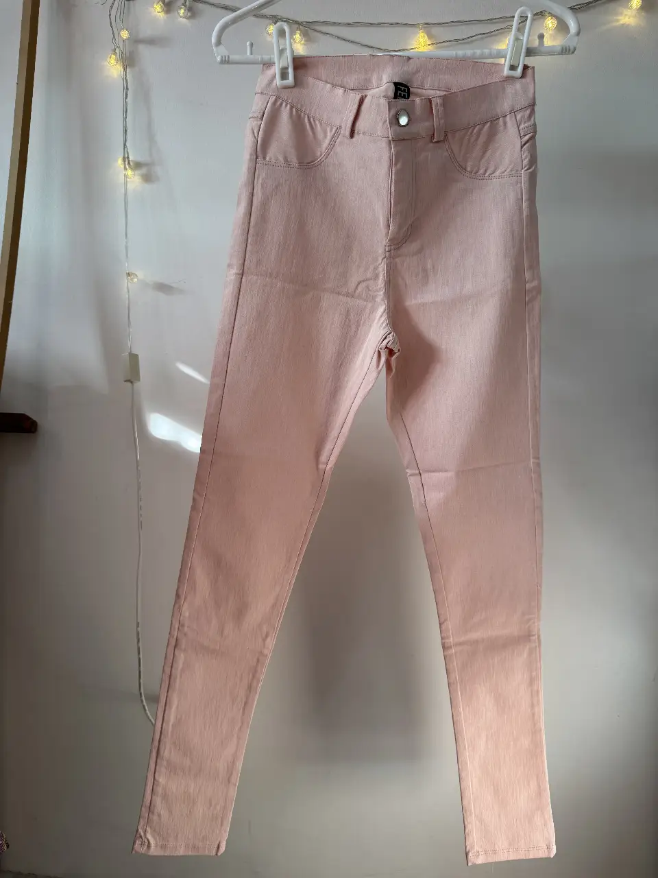 Pantalón sastrero de color rosa, tiro medio, con bolsillos delanteros y traseros. Ideal para un look casual o de trabajo.