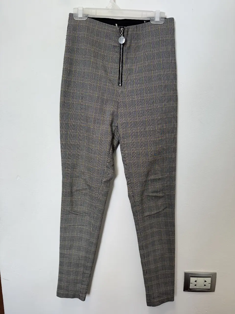 Pantalón sastrero de mujer, con estampado a cuadros en tonos grises y amarillos. Tiene cierre frontal y un detalle metálico. Marca Zara, talle XS.
