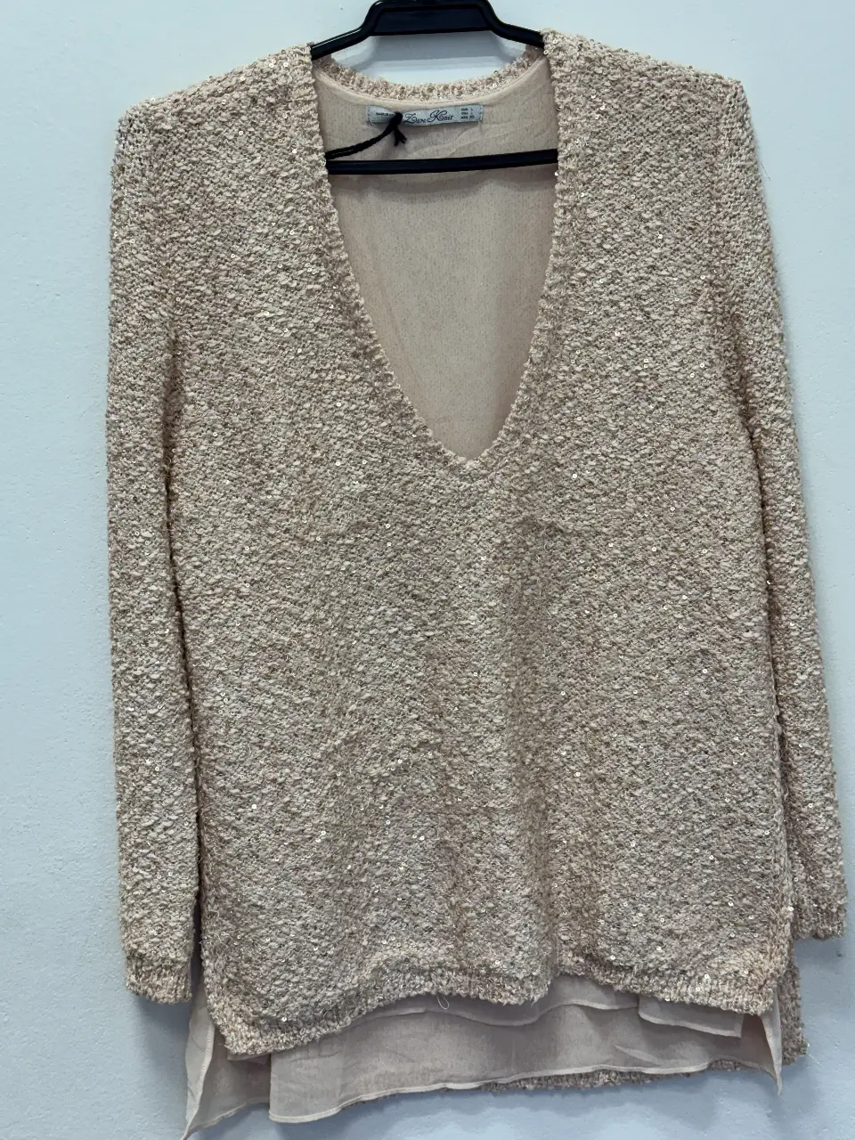 Sweater de mujer en color crudo con diseño texturizado y lentejuelas. Cuello en V y mangas largas. Ideal para un look elegante y sofisticado.