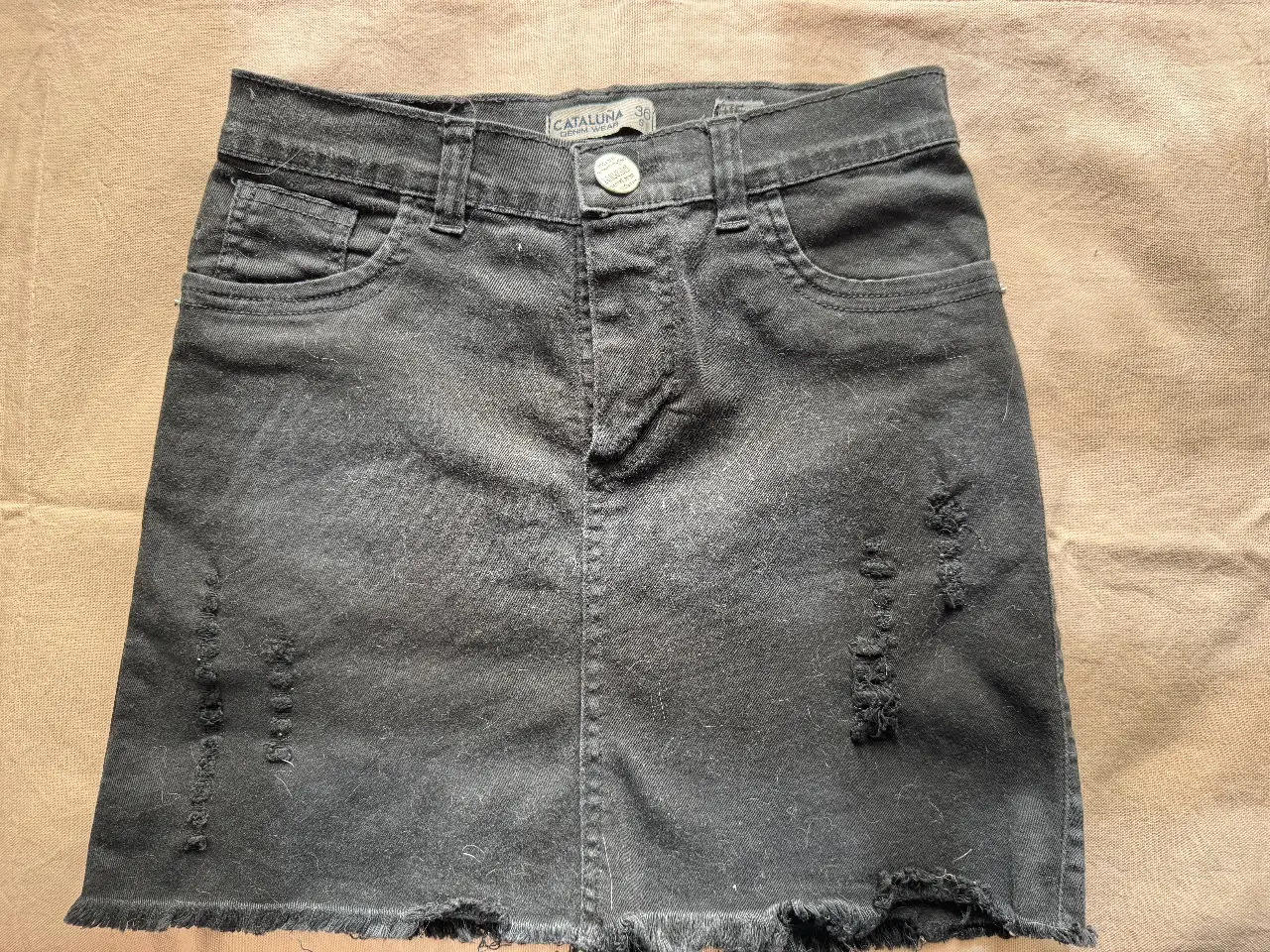 Minifalda de jean negra con detalles rotos. Ideal para un look casual y moderno. Marca Catalina.