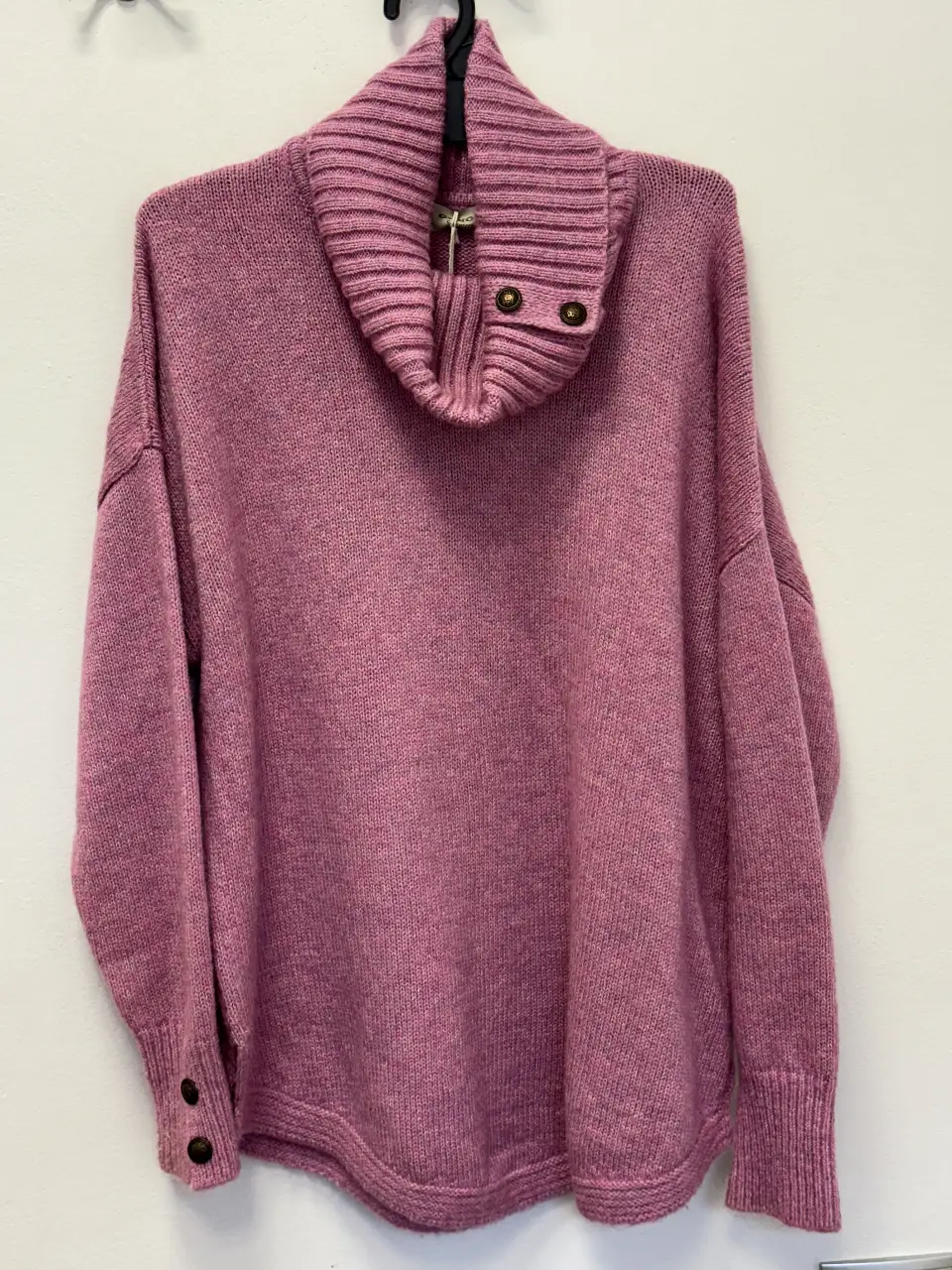 Sweater polera de tejido grueso en color rosa. Cuello alto con botones decorativos y puños con botones. Ideal para un look casual y abrigado.