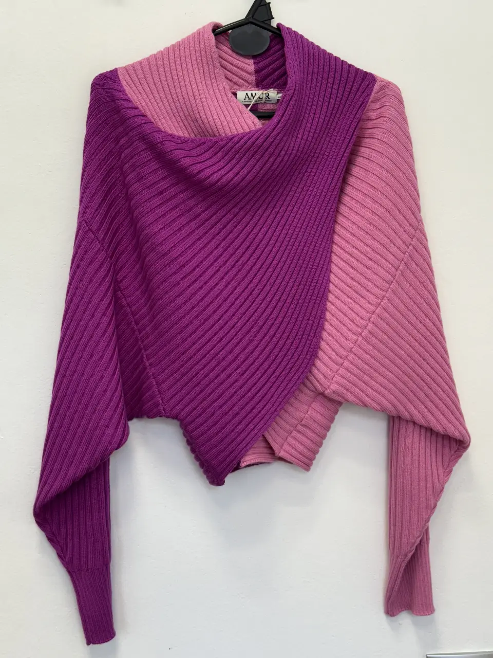 Sweater asimétrico de dos colores, rosa y violeta, con cuello alto. Ideal para un look moderno y abrigado.