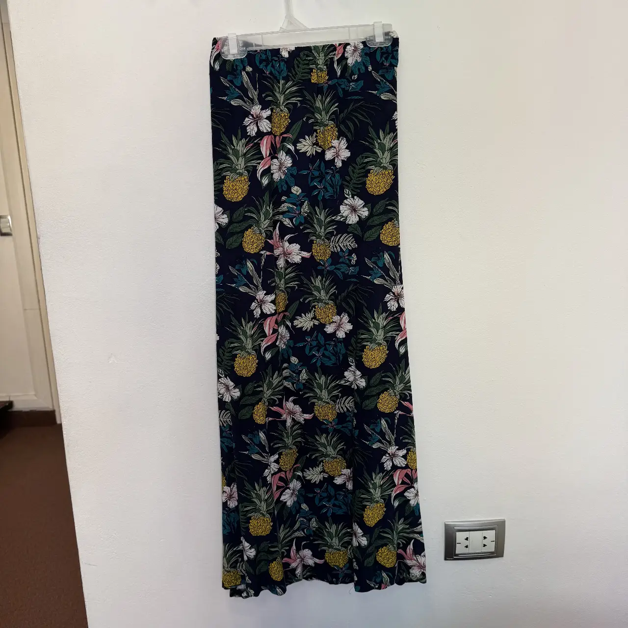 Pollera larga de mujer con estampado de piñas y flores sobre fondo azul oscuro. Ideal para un look fresco y veraniego.