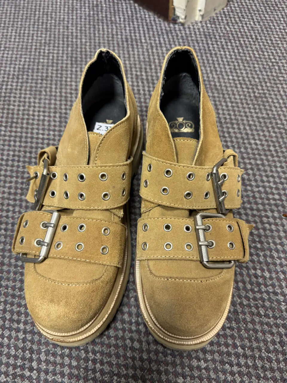 Botines de gamuza color marrón con hebillas y detalles metálicos. Estilo moderno y urbano, ideales para un look casual con un toque de rebeldía.
