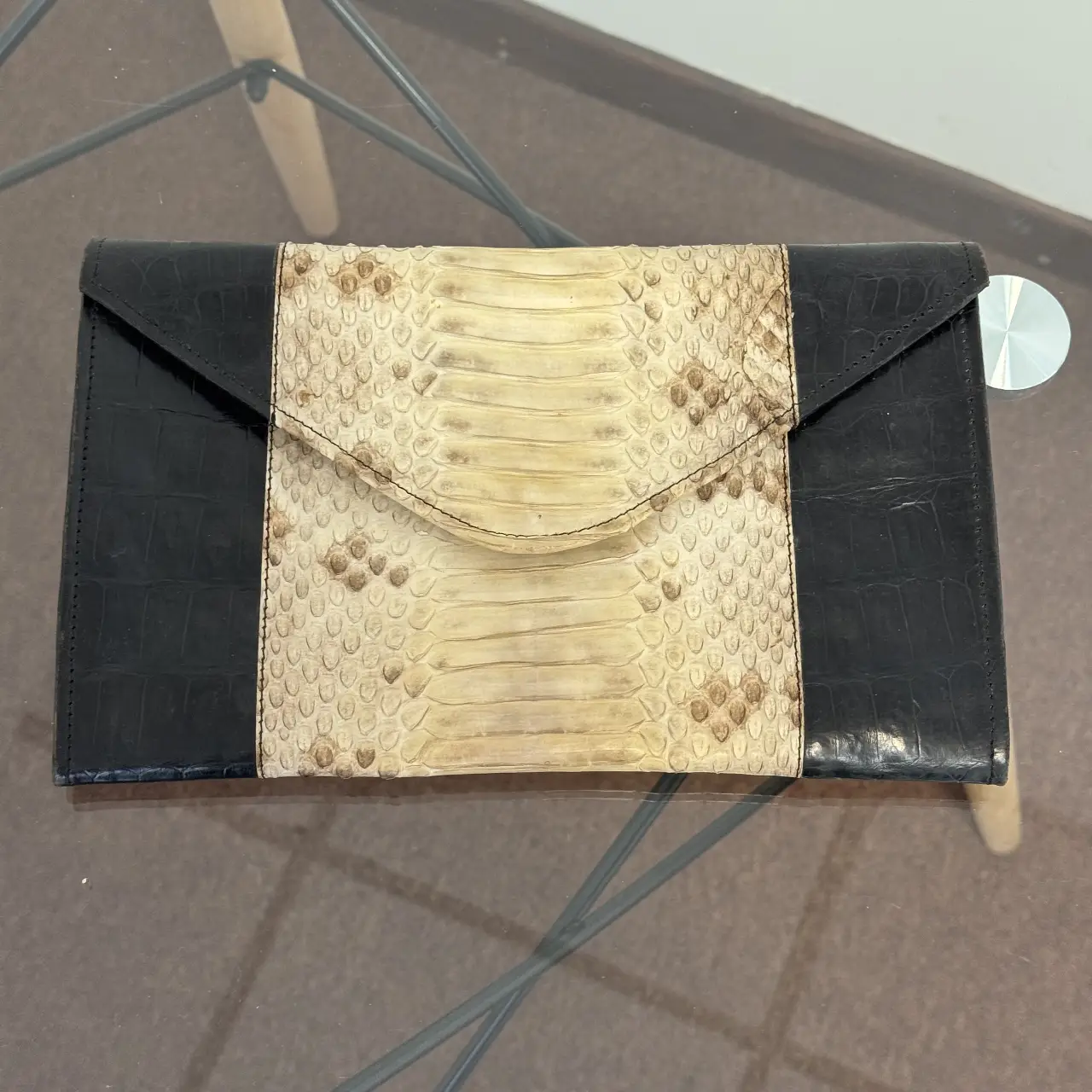Cartera de mano tipo sobre, combinada con cuero negro y detalles en piel de serpiente. Ideal para eventos especiales o para darle un toque sofisticado a tu look.