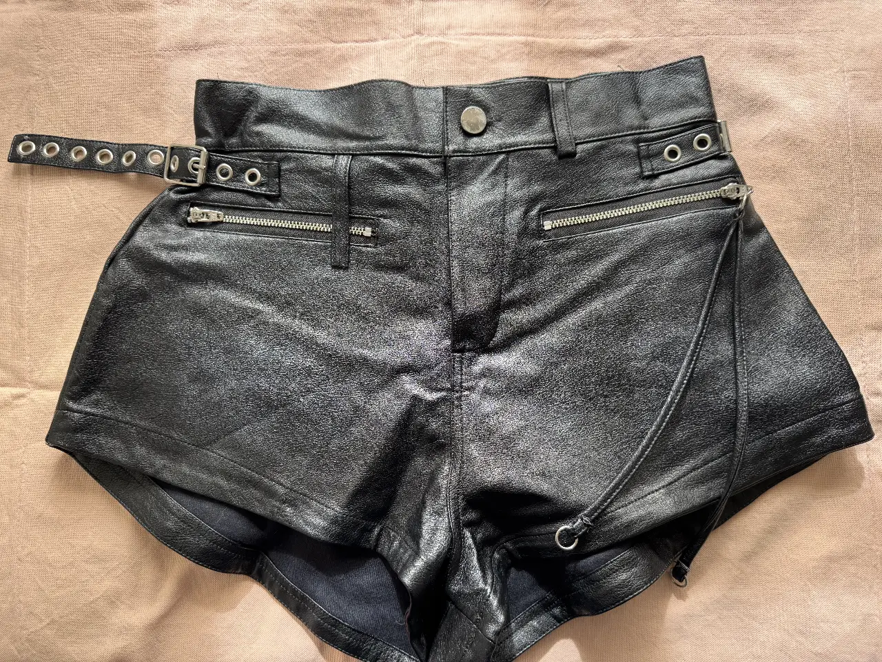 Short de cuero sintético negro con detalles de cierres y cinturón con hebillas. Ideal para un look rockero y audaz.