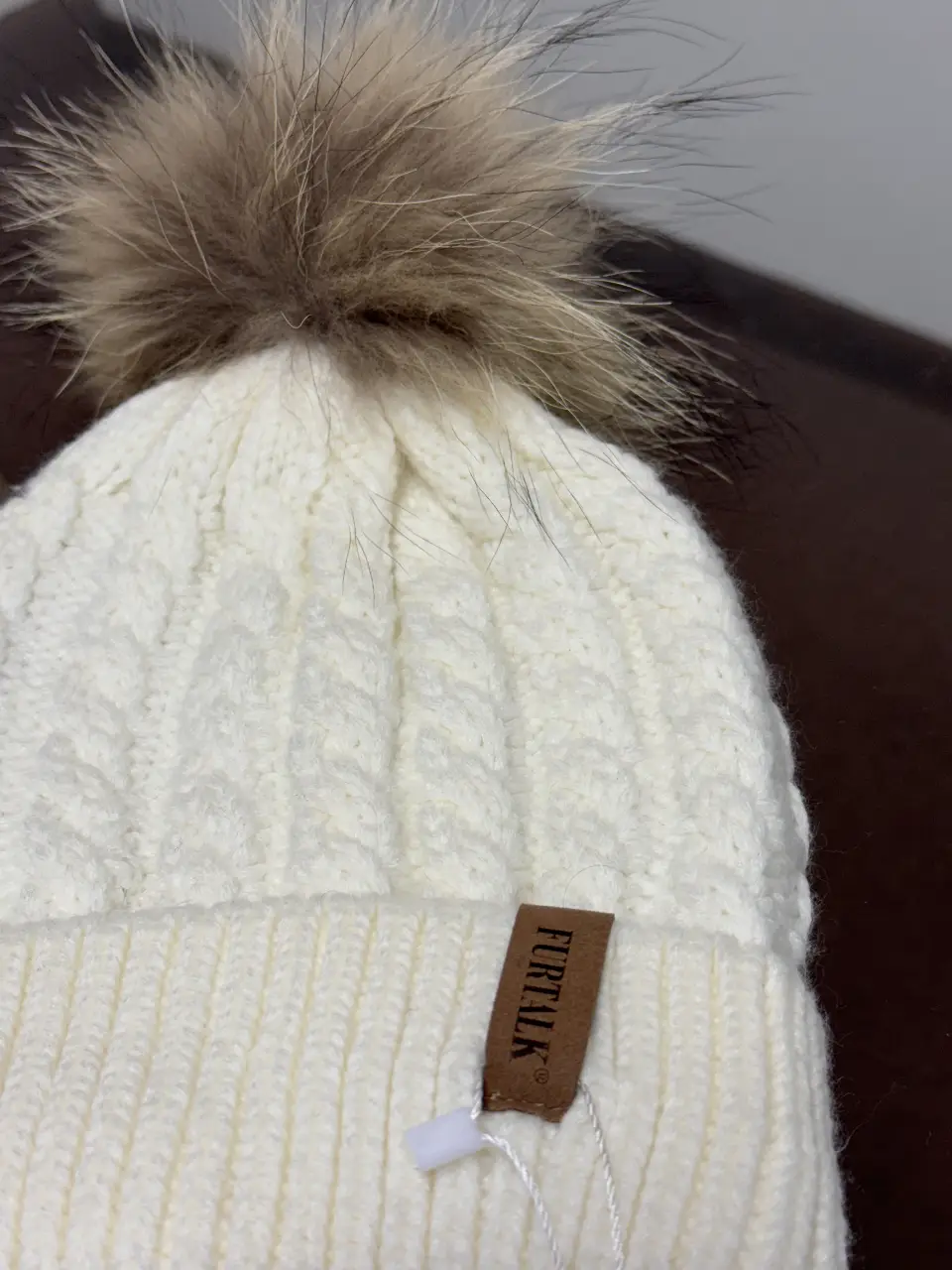 Gorro tejido blanco con pompón de piel marrón. Ideal para el invierno, este gorro ofrece calidez y estilo. Perfecto para combinar con cualquier outfit casual.