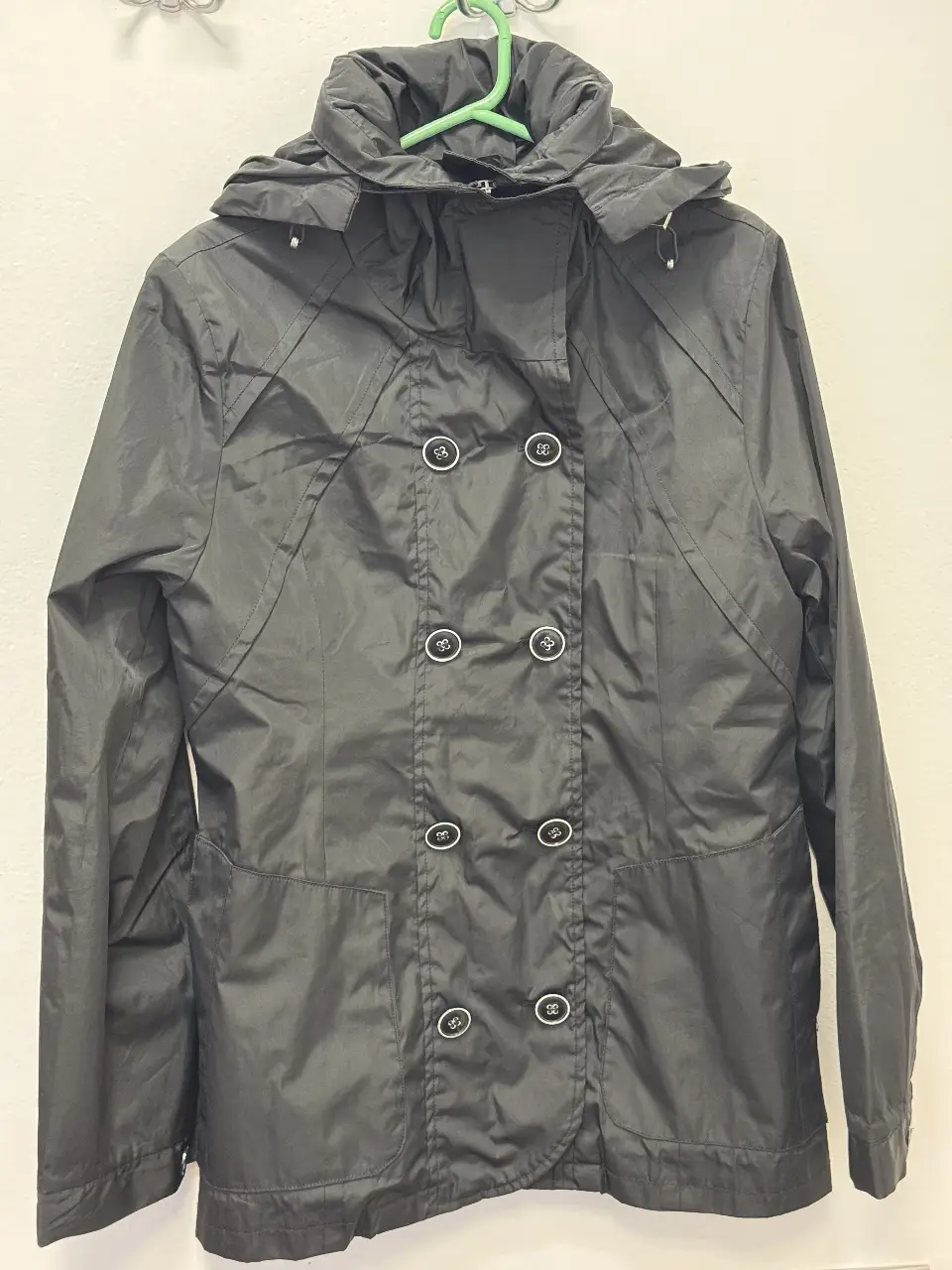 Campera negra con capucha, doble abotonadura y bolsillos. Ideal para lluvia y uso casual.