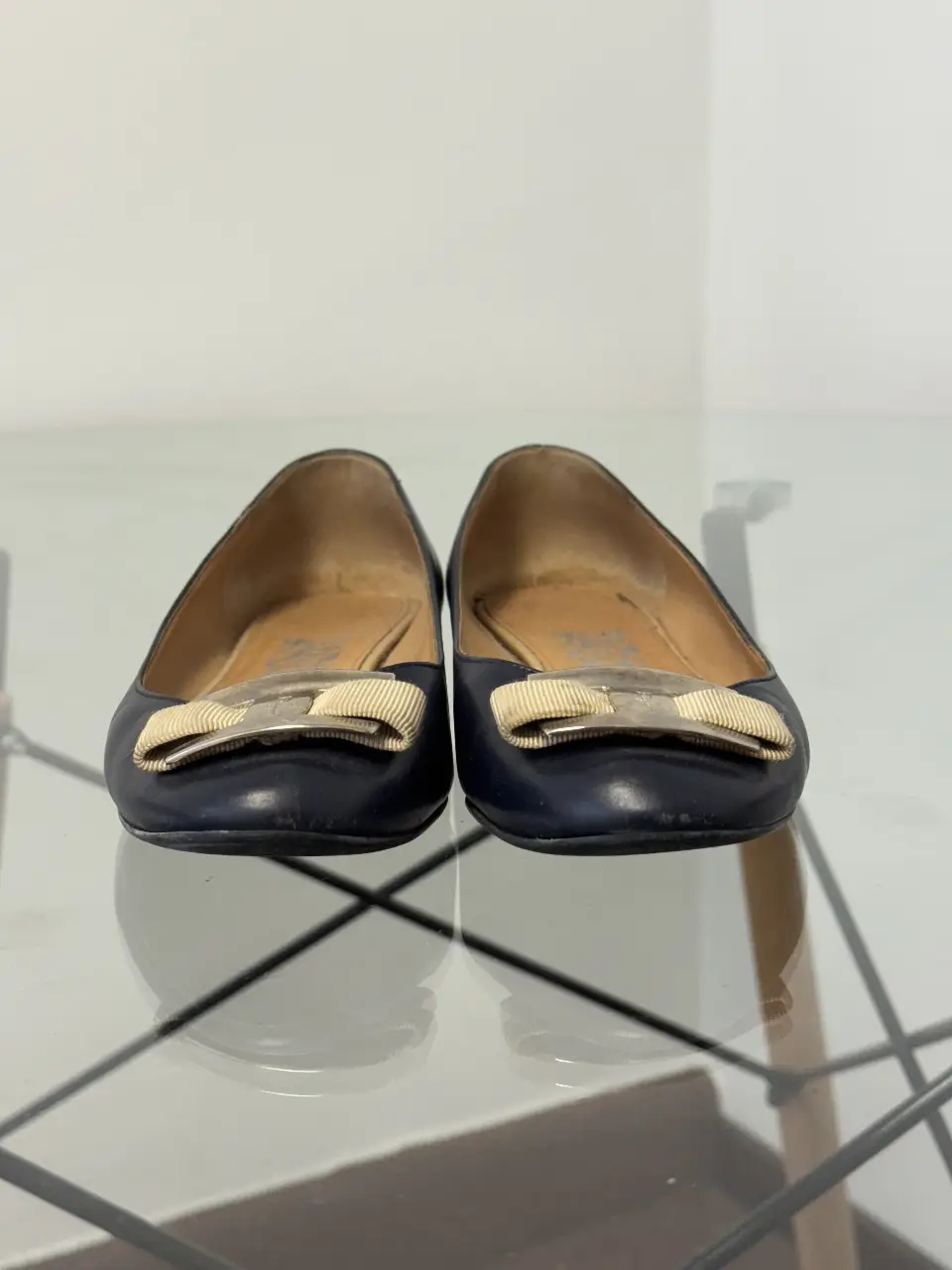 Ballerinas de cuero azul marino con moño dorado. Un clásico de la marca Ferragamo, ideales para un look elegante y cómodo.
