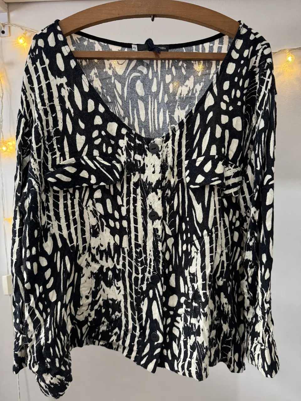 Blusa de mujer con estampado abstracto en blanco y negro. Diseño con botones y mangas largas. Talle XS.
