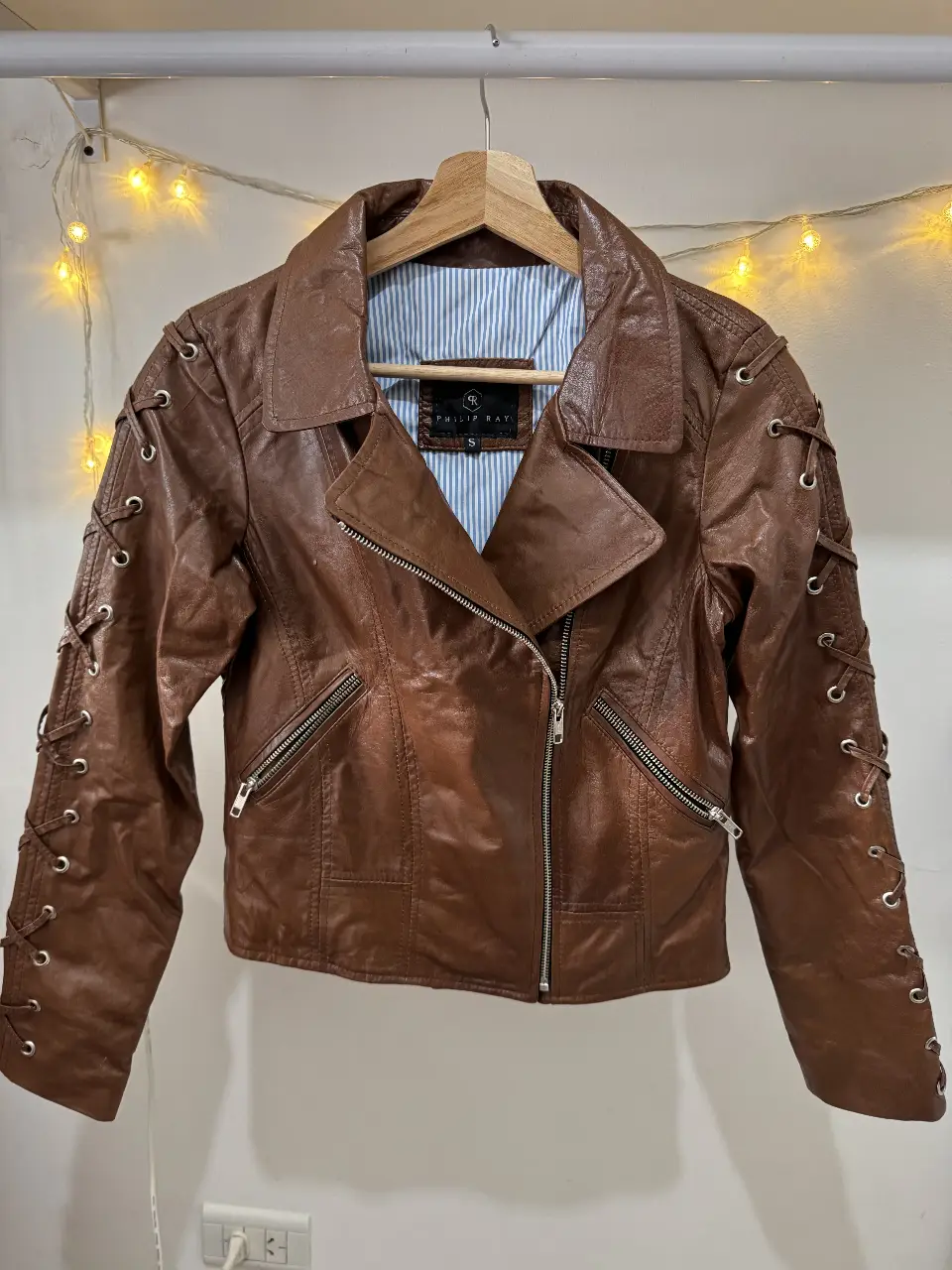 Campera biker de cuero marrón con detalles de cordones en las mangas y espalda. Ideal para un look rocker y canchero.