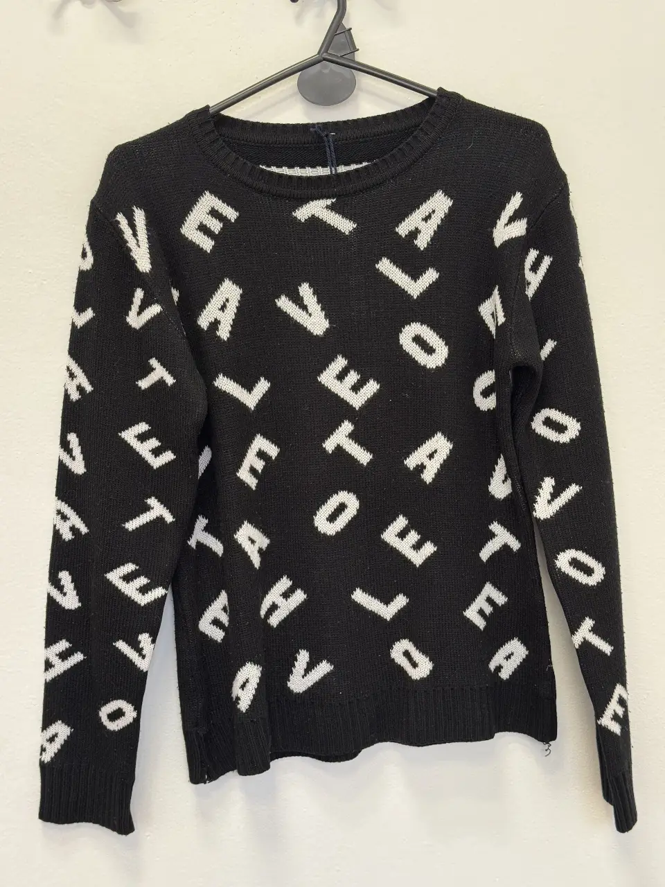 Sweater negro de punto con estampado repetido de la palabra "LOVE" en blanco. Ideal para un look casual y moderno.